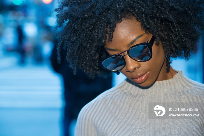 戴着镜面太阳镜的非裔美国妇女在城市场景中