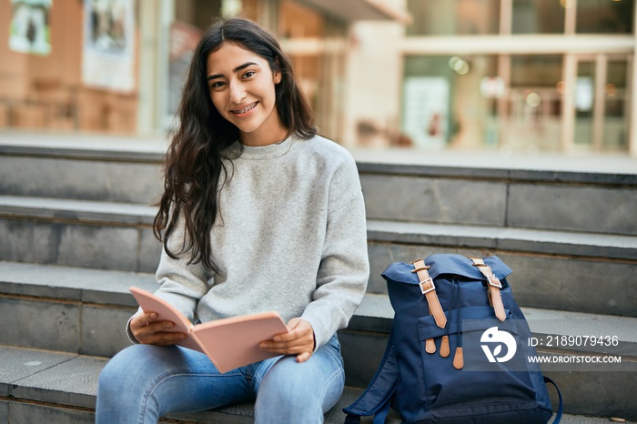 Young middle east student girl smiling happy reading book at the university.