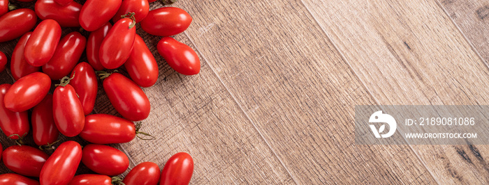 Fresh cherry tomatoes over wooden table background.