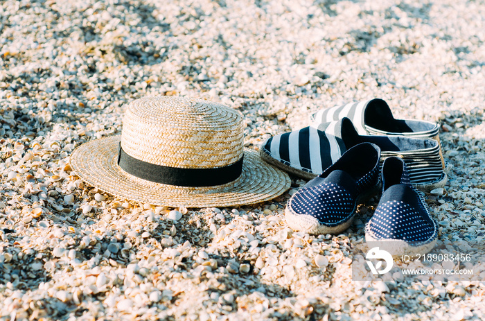 Straw hat and espadrilles lying on the sand on the beach. Summer concept. Holiday relaxing, beach va