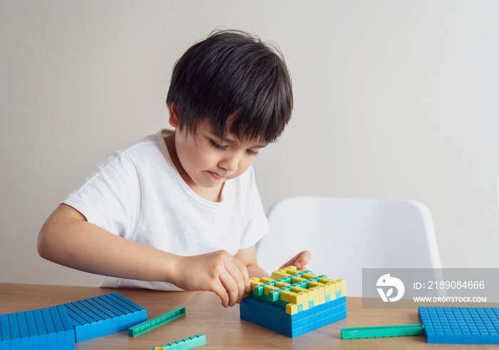 小学生使用塑料块计数，男孩用彩色堆叠盒学习数学，蒙台梭利