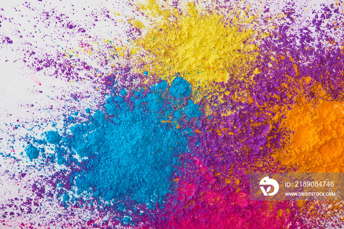 top view of explotion of yellow, purple, orange and blue holi powder on white background