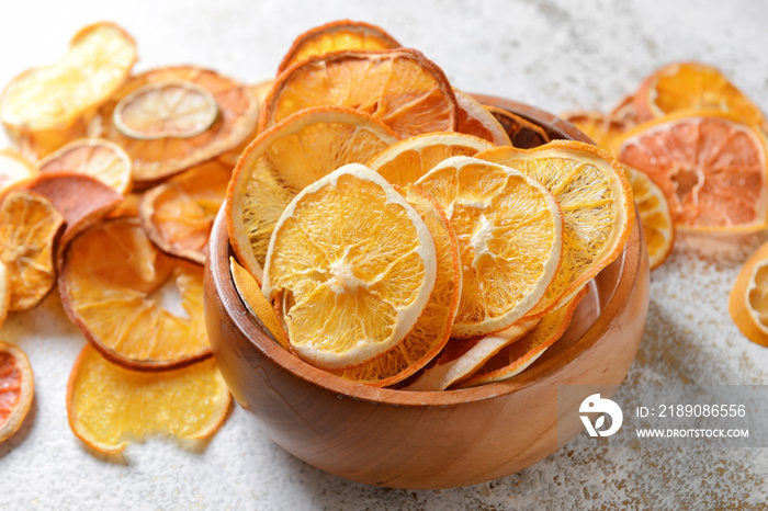 Bowl with dried citrus fruits on light background