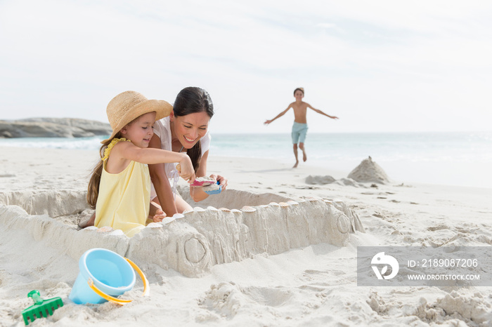 Mother and daughter building sandcastle on beach