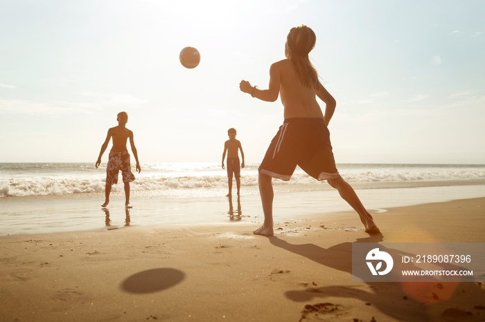 Children playing soccer on shore at beach