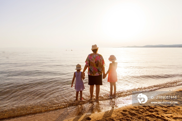 Rearview of family relax on sand beach at sunset during summer vacation