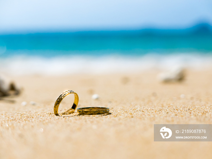 Honeymoon. Two wedding rings on sandy beach