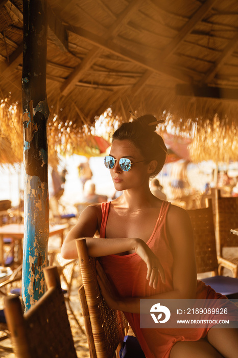 Young woman wearing sunglasses sitting in the beach bar