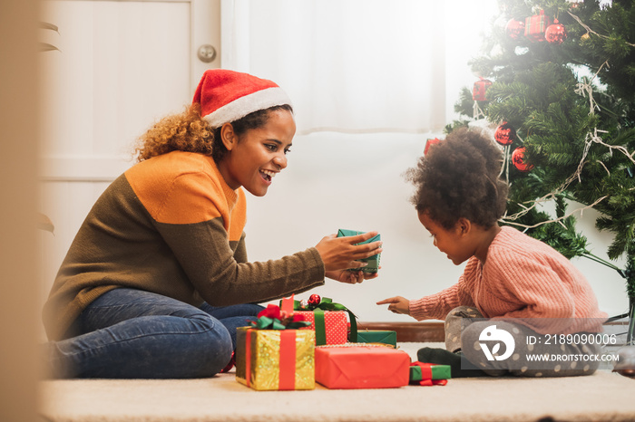 Young black african mother giving Christmas present gift box to her daughter, merry christmas and ha