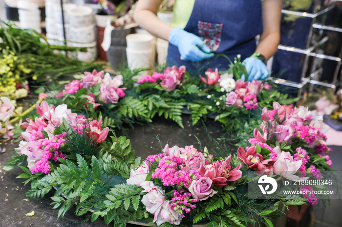 The florist creates a wreath of exotic flowers in pink tones from orchids, roses, and other flowers,