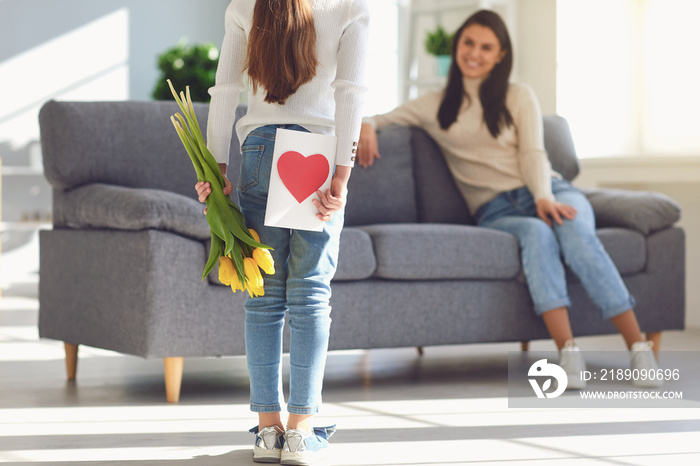 Happy mothers day. Daughter congratulates hugs his mother holds a bouquet of flowers in the room.