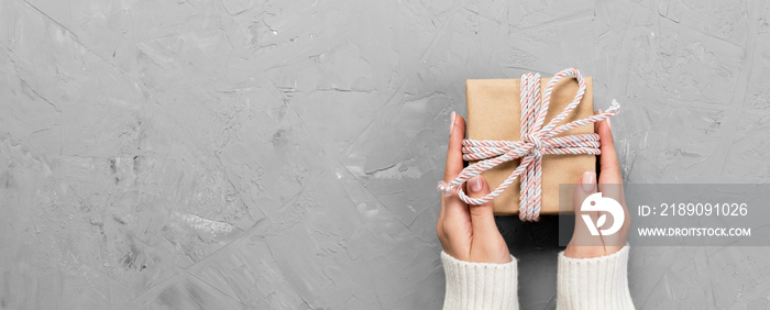 Woman hands give wrapped valentine or other holiday handmade present in paper with red ribbon. Prese