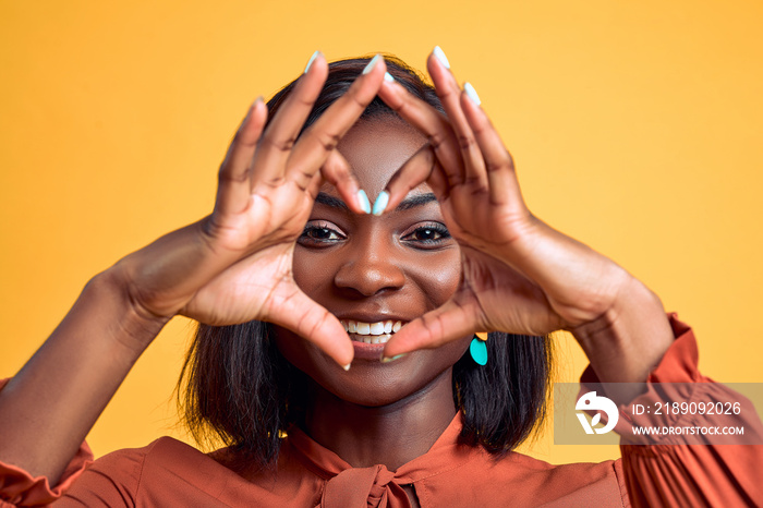 Smiling young african american woman showing shape heart with hands heart-shape sign posing isolated