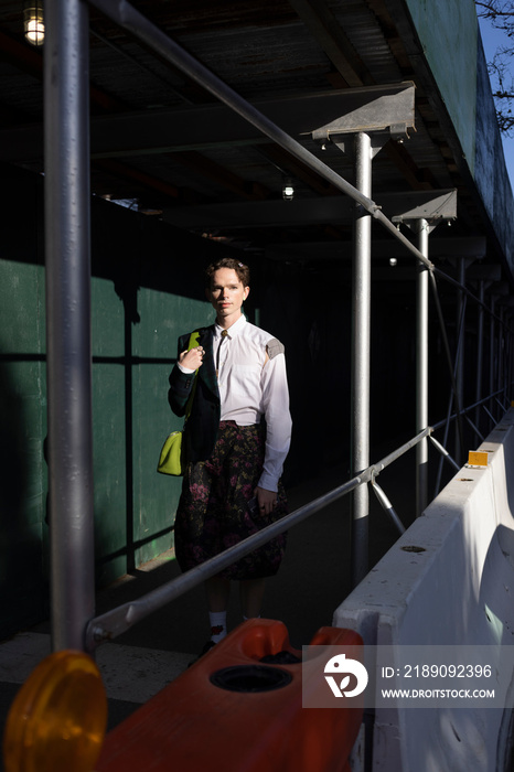 fashion portrait of non-binary person in city with dramatic sunlight