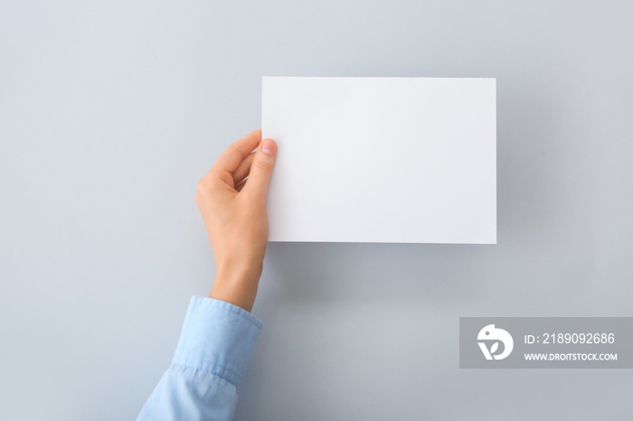 Female hand with blank paper on light background