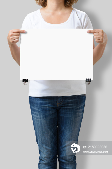 一个女人拿着一张空白的A3海报模型，被隔离在灰色背景上。