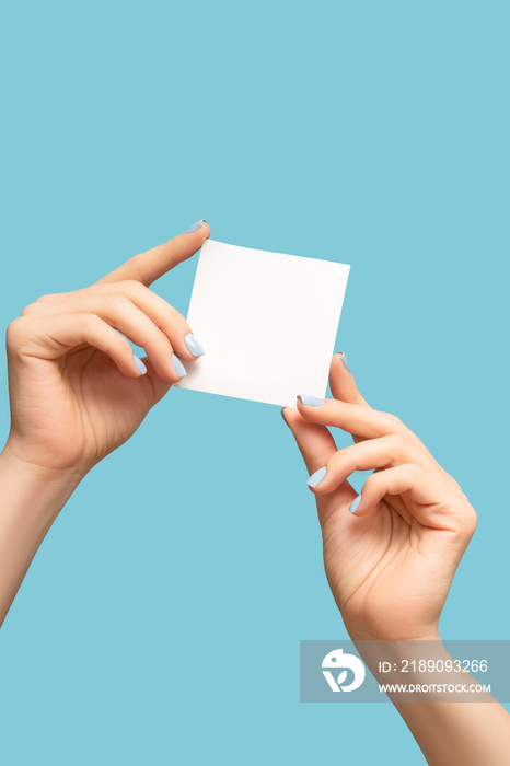 修蓝色指甲的女性手拿着一张白色空白信息卡。女性手上有纸质卡片横幅