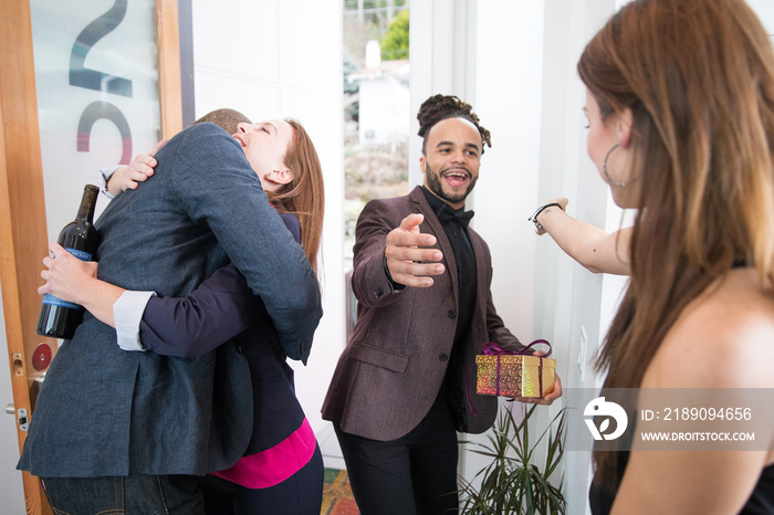 Group of friends greeting each other at door of home