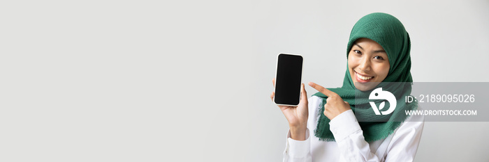 Happy smiling muslim woman pointing at black smartphone screen