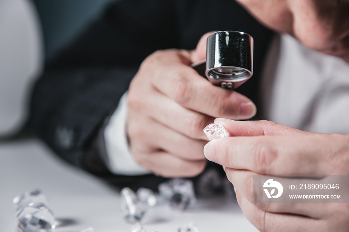 Businessman jeweler during the evaluation of jewels with magnifier. Jeweler looking at diamonds or L