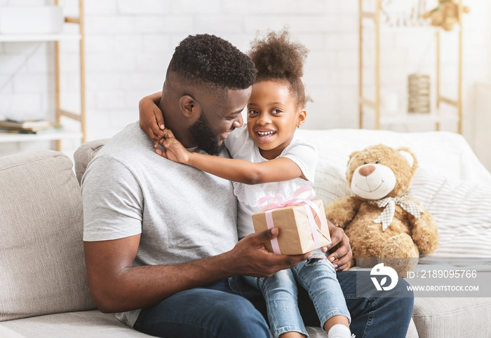 Adorable african girl sitting on dads lap, celebrating birthday