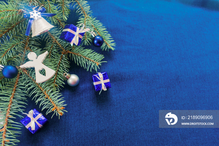 蓝色圣诞背景，圣诞树枝上装饰着礼盒、铃铛和wh