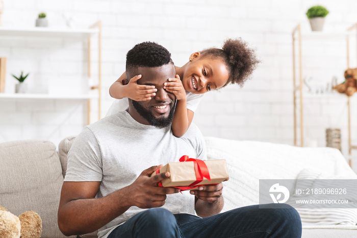 Cute preschool african girl covering her dad eyes