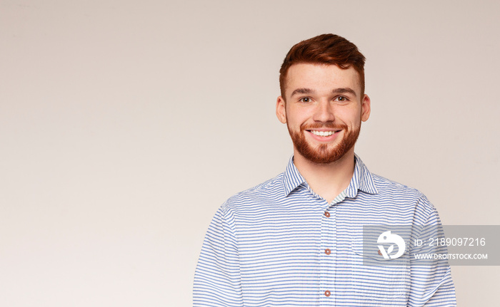 Portrait of smiling millenial guy on beige background