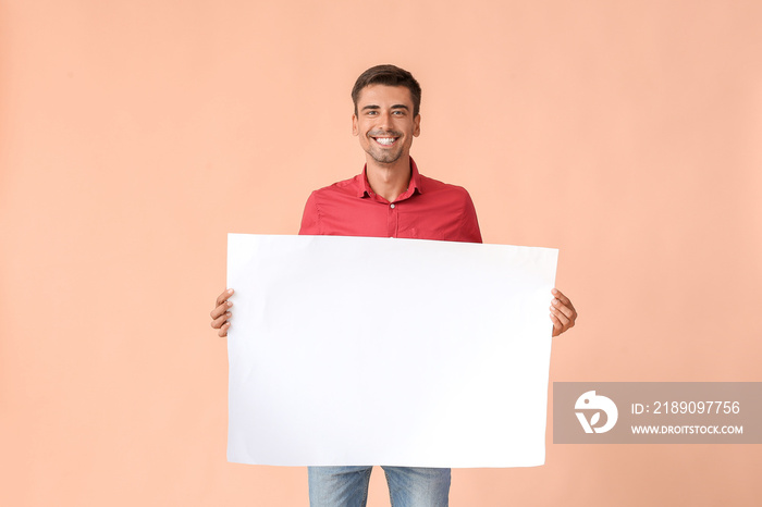 Young man with blank paper sheet on color background