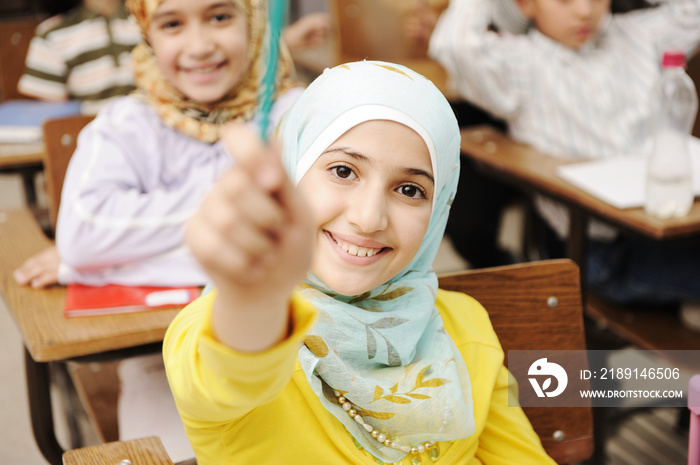 Adorable Muslim girl in classroom with her friends