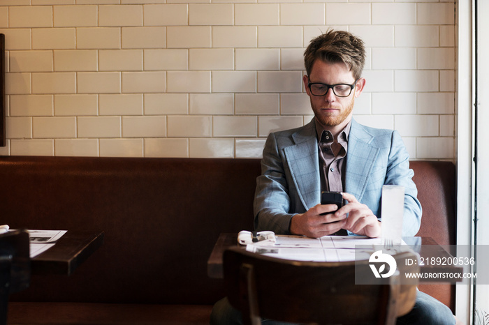 Young man texting in restaurant