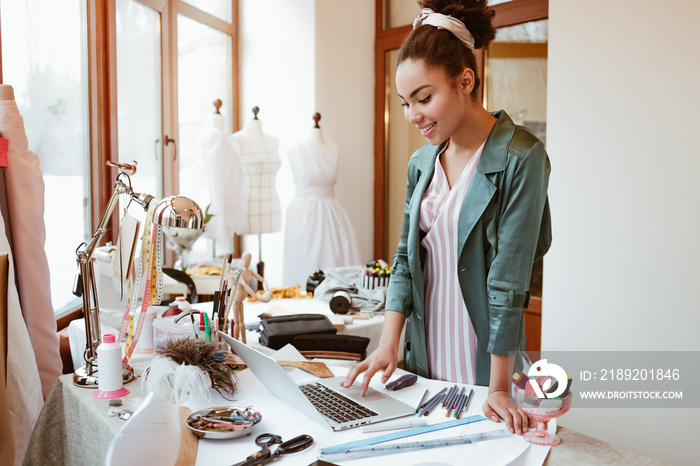 Checking online sales. Young woman tailor with laptop is answering emails