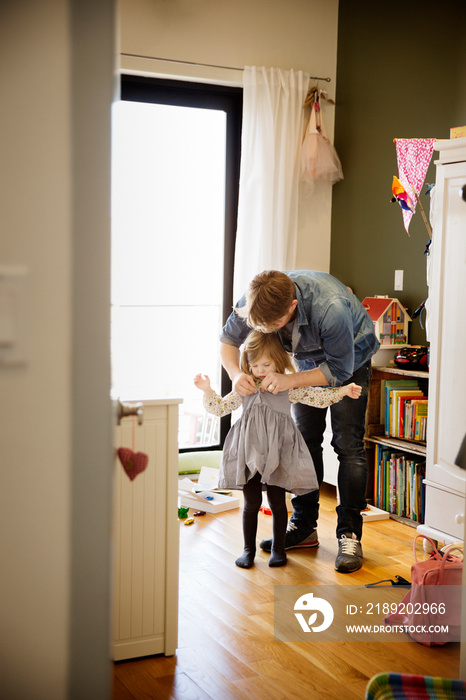 Father helping daughter (4-5) get dressed