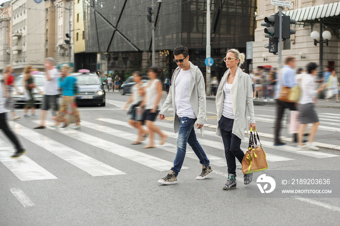 Fashionable couple crossing road at pedestrian zebra crossing