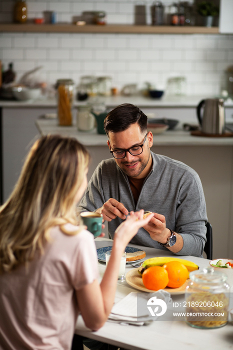 Happy man enjoying in breakfast with his girlfriend. Loving young couple drinking coffee and eating 