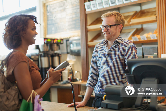 Young adult woman paying for purchase using debit machine