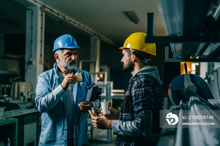 workers having lunch break standing indoor industry warehouse