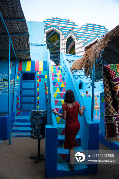 A young woman in a red dress climbing some colorful stairs that go up to a beautiful terrace of a tr