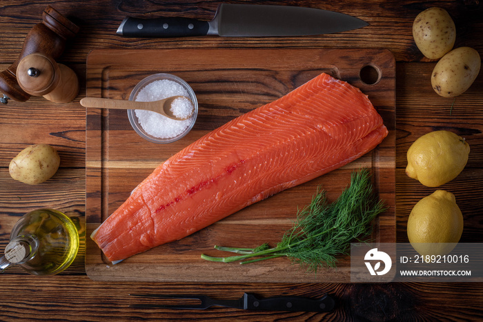 whole raw salmon fillet on wooden cutting board