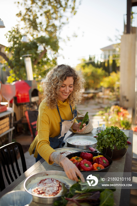 Smiling woman preparing food on table against sky in yard