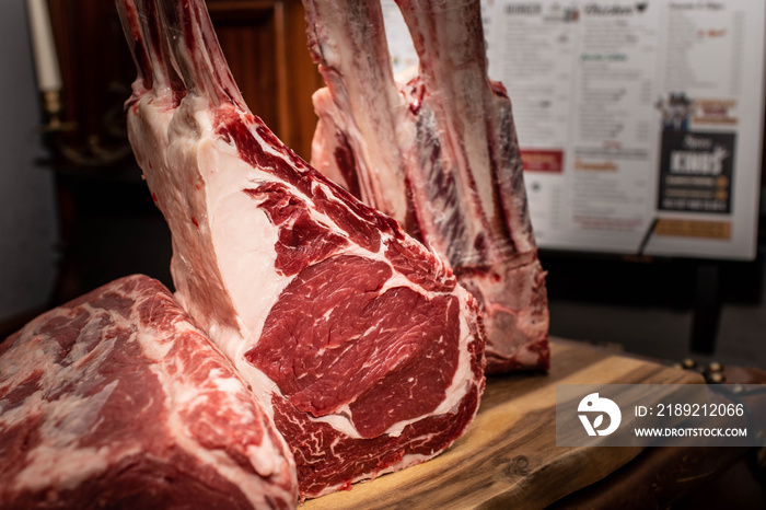 Tomahawk Steaks dryaged auf Holzbrett im Restaurant mit Metrofliesen