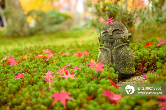 Red Maple leaf on head of Jizo sculpture doll (little Japanese Buddhist monk doll rock) in Japanese 