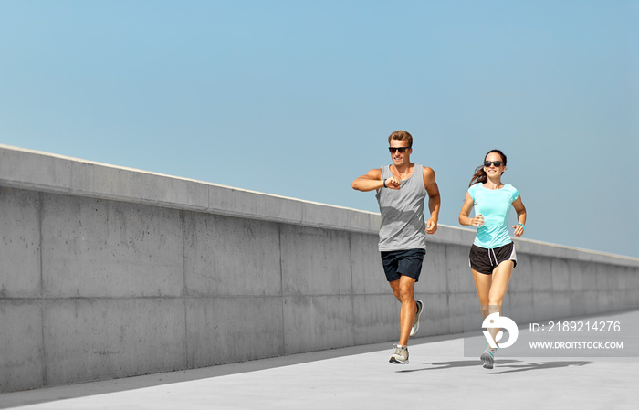 健身、运动和生活方式理念——穿着运动服、戴着墨镜的幸福情侣在户外跑步