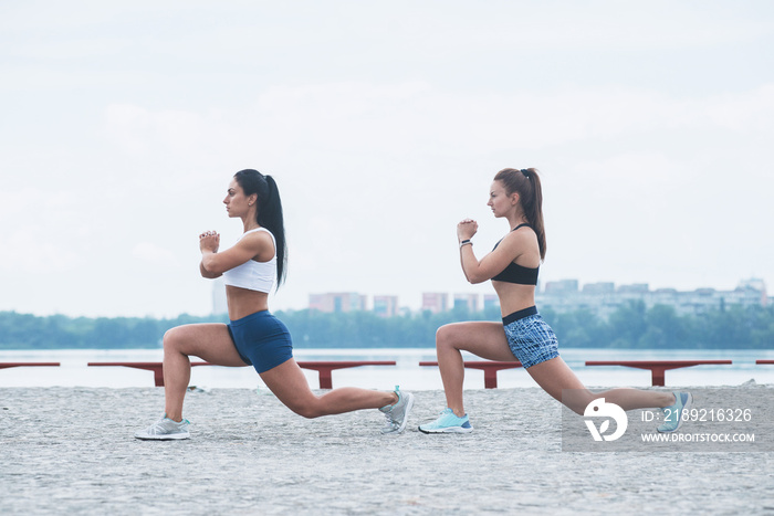 两个健康的女人在跑步锻炼后做伸展运动。海滨的积极生活方式