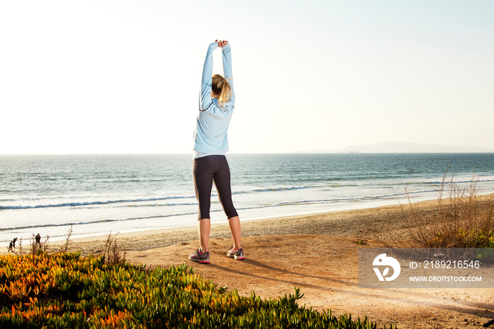 Woman stretching on beach at sunset