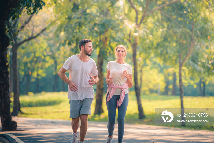 Portrait of Young couple running in the park at sunset. Concept sport and love. Warm tone.