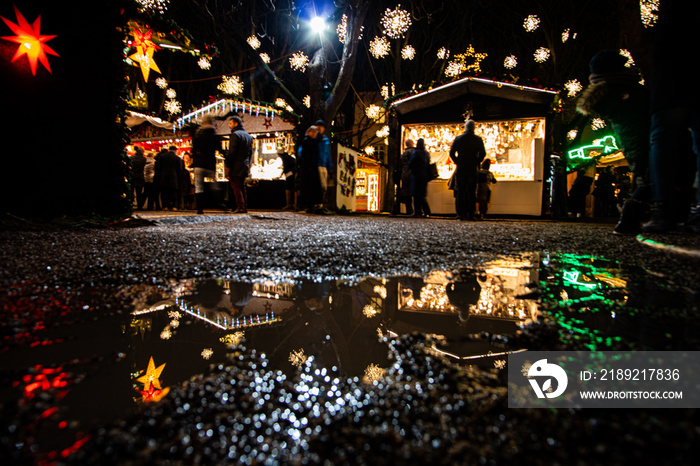 Weihnachtsmarkt in Basel auf dem Münsterplatz mit Spiegelung in der Pfütze