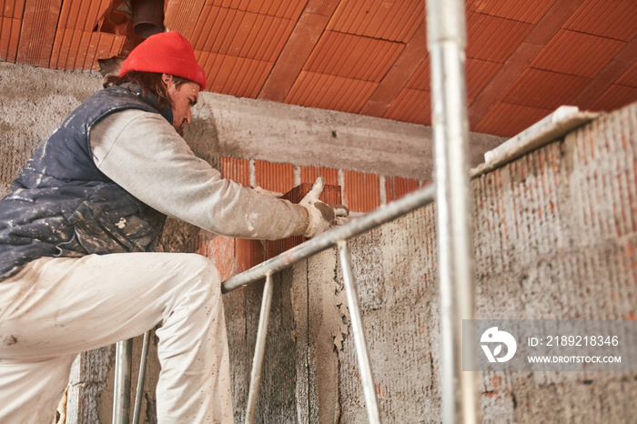 Real construction worker making a wall inside the new house.