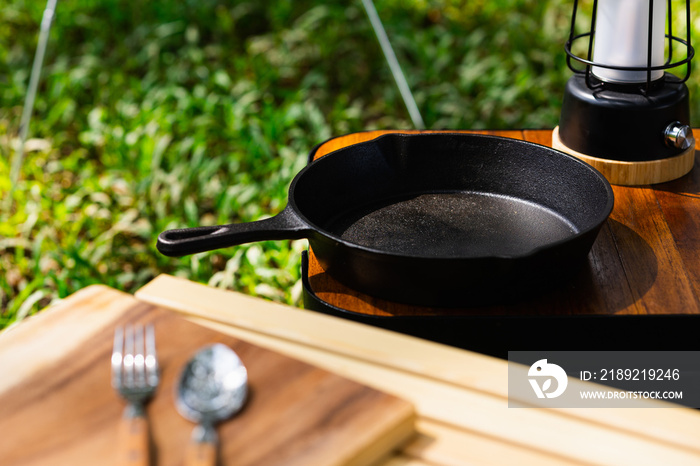 木制桌子上的铁锅和露营配件。用于在森林中露营的设备。夏季阳光充足