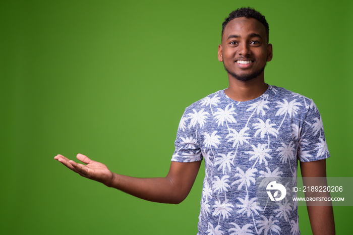 Young handsome African man against green background